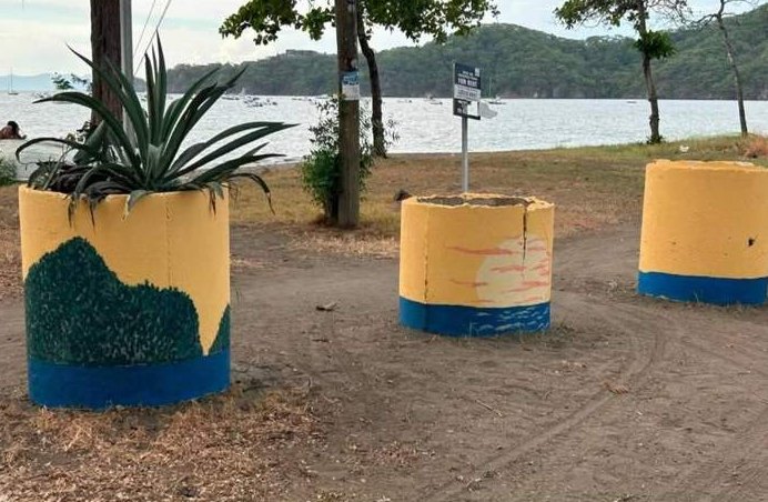 Painted concrete barrels at a beach entrance.
